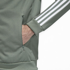 Adidas Beckenbauer Track Jacket Men's in trace green, side profile showing long sleeves with white 3-Stripes, ribbed cuffs, and regular fit.
