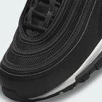 Close-up zoom on the front of the Nike Air Max 97 Women's black trainers, showing the wavy design lines and tongue branding.