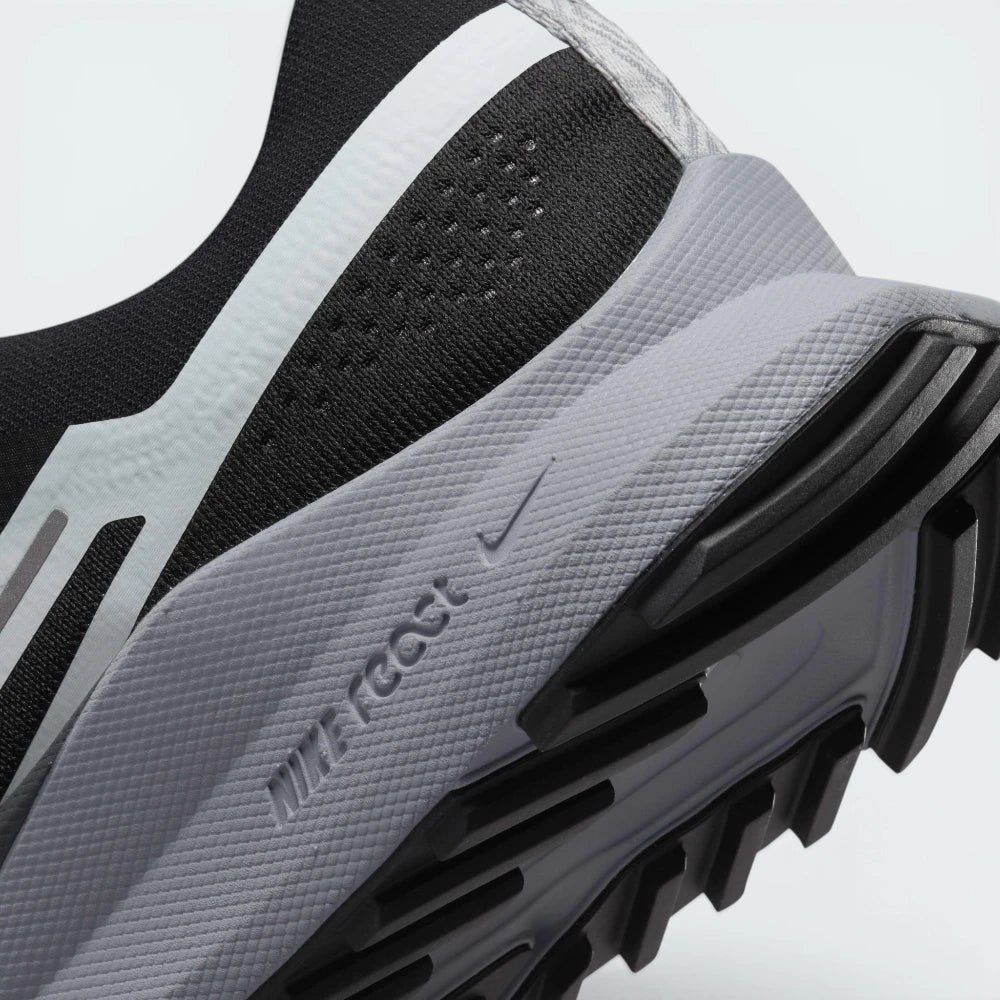 Highlights the "unreal" clean finish where the responsive React cushioning wall bonds securely to the high-friction, generative trail rubber base.