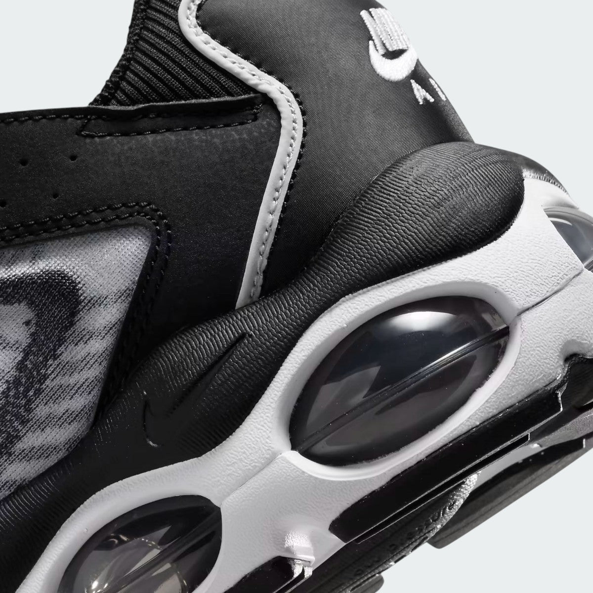 Close-up zoom on the side of the Nike Air Max TW trainers, detailing the haptic texture, angular synthetic overlays, and the visible Air unit.
