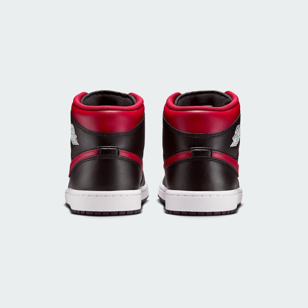 Rear view of the Air Jordan 1 Mid Men's black trainers, focusing on the red Wings logo on the collar and contrasting heel panel.