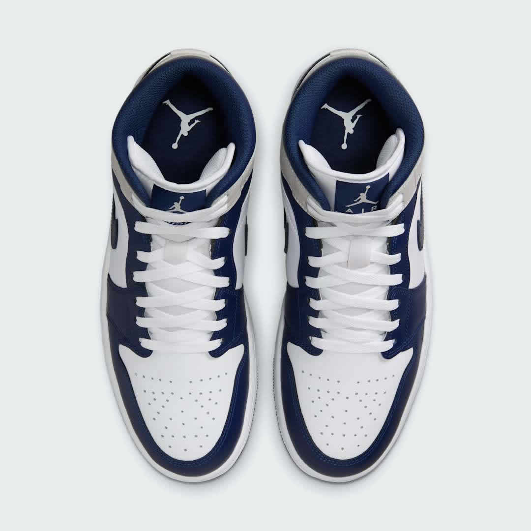 Top-down view of a pair of Air Jordan 1 Mid Men's trainers in white, blue, and black, highlighting their classic silhouette and lace-up closure.