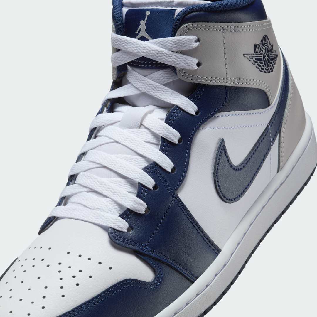 Close-up zoom on the front of the Air Jordan 1 Mid Men's trainers, showing the perforated toe box, lacing system, and textured leather upper.