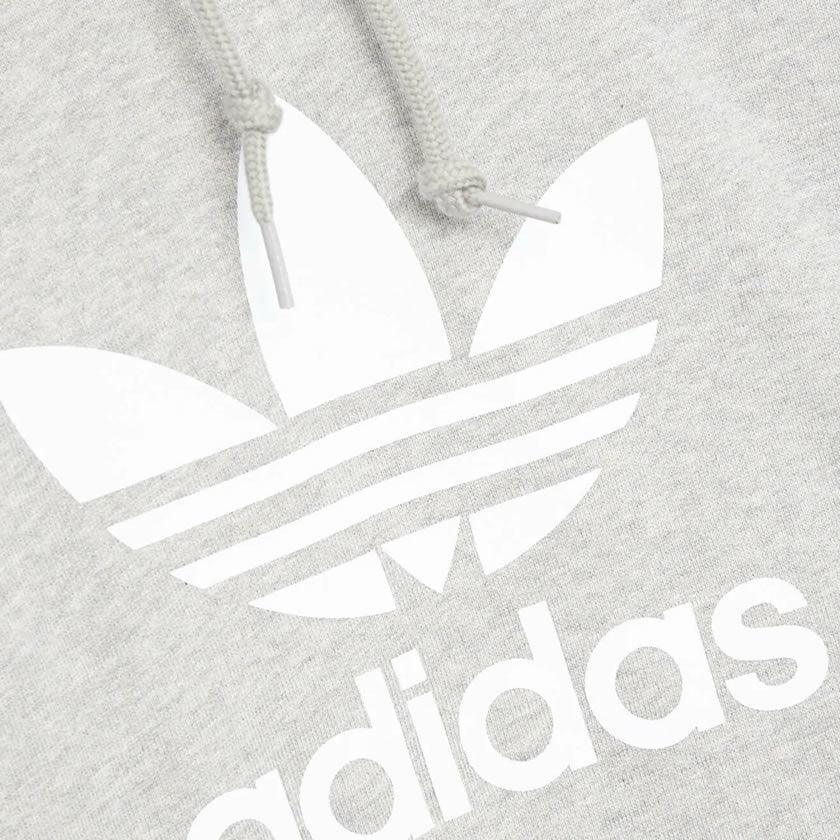Close-up zoom on the Adidas Trefoil Hoodie Men's in grey heather, showing the soft French terry fabric texture and the embroidered (or printed) Trefoil logo detail.