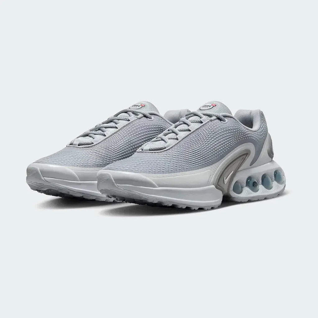 Angled view of two Nike Air Max DN Men's grey running shoes, side by side, showcasing their bold, modern design and prominent Air unit.