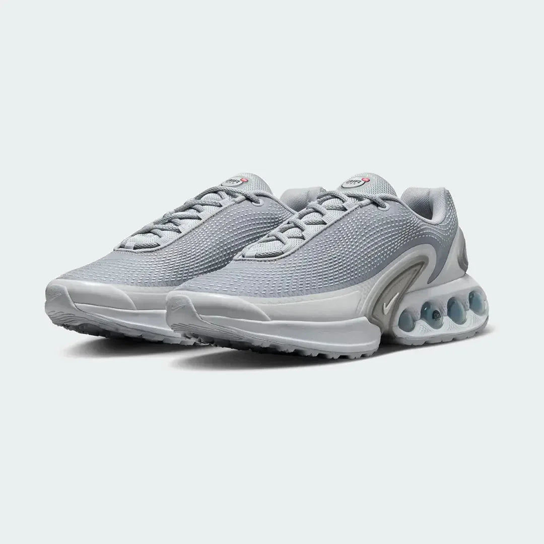 Angled view of two Nike Air Max DN Men's grey running shoes, side by side, showcasing their bold, modern design and prominent Air unit.