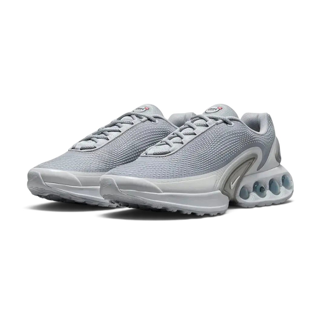 Angled view of two Nike Air Max DN Men's grey running shoes, side by side, showcasing their bold, modern design and prominent Air unit.