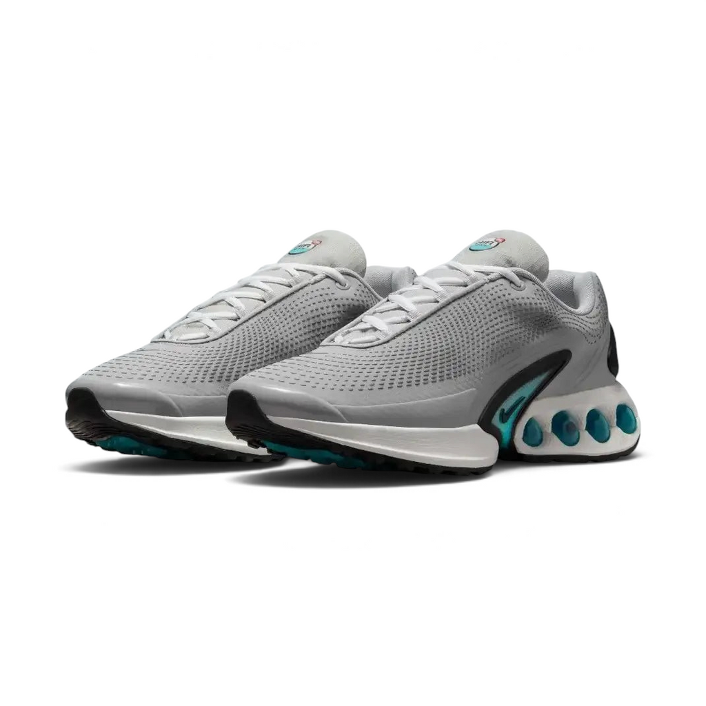 Angled view of two Nike Air Max DN Men's grey running shoes, side by side, showcasing their bold, modern design and prominent Air unit.