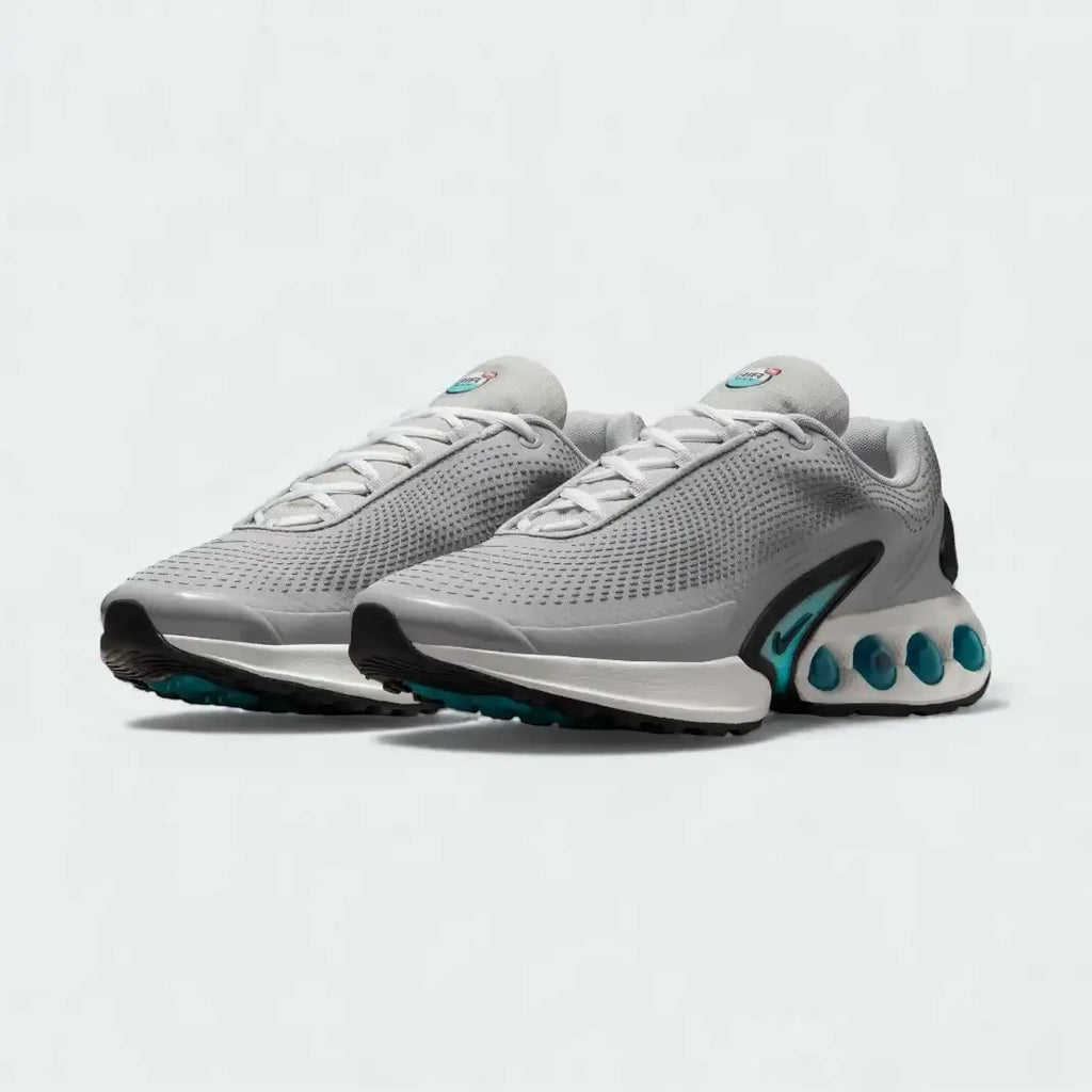 Angled view of two Nike Air Max DN Men's grey running shoes, side by side, showcasing their bold, modern design and prominent Air unit.