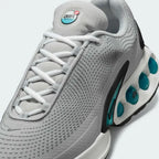 Close-up zoom on the front of the Nike Air Max DN Men's grey running shoes, showing the mesh upper texture, haptic print details, and lacing system.