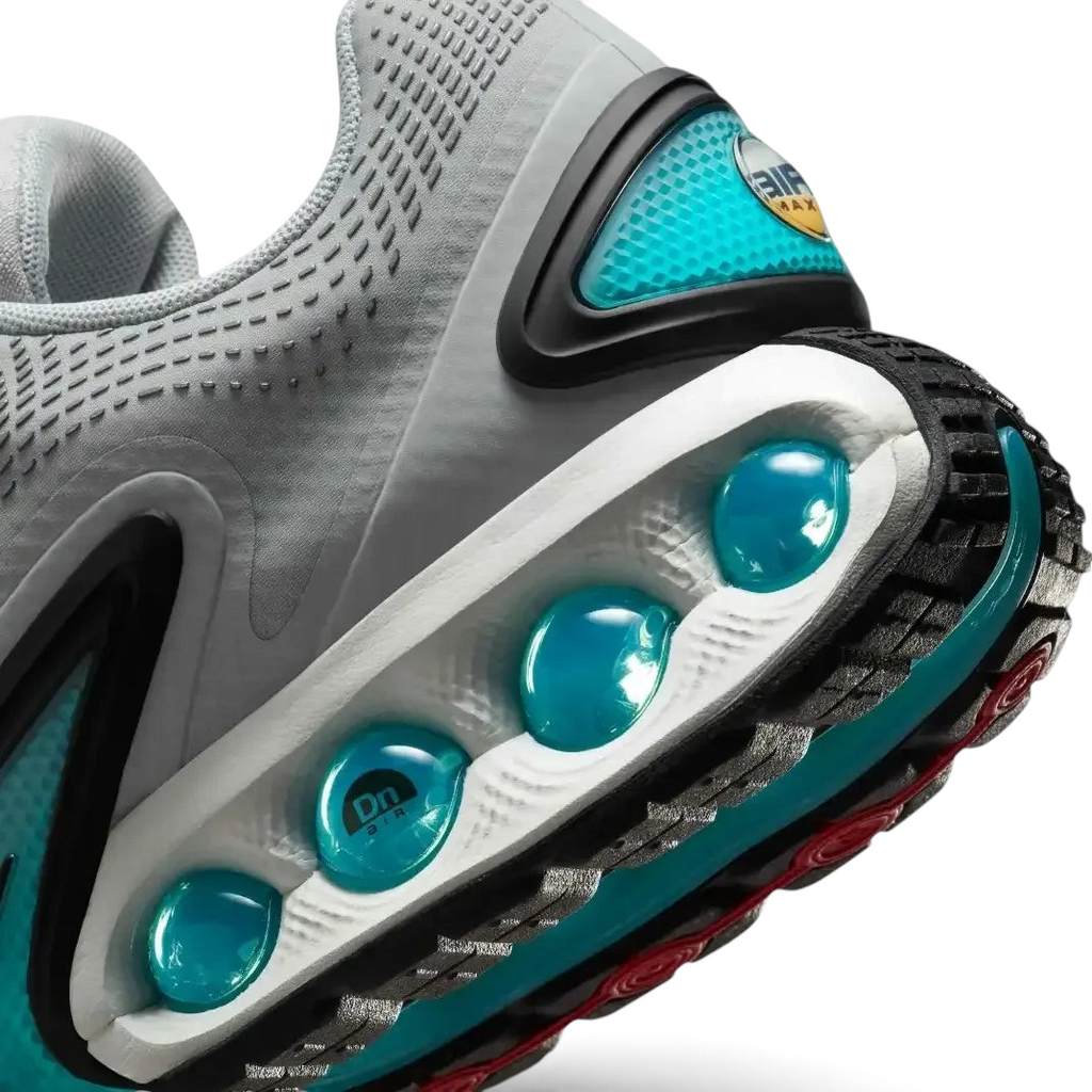 Detailed zoom on the outsole and midsole of the Nike Air Max DN Men's grey running shoes, highlighting the dual-pressure Dynamic Air cushioning system and robust rubber outsole.