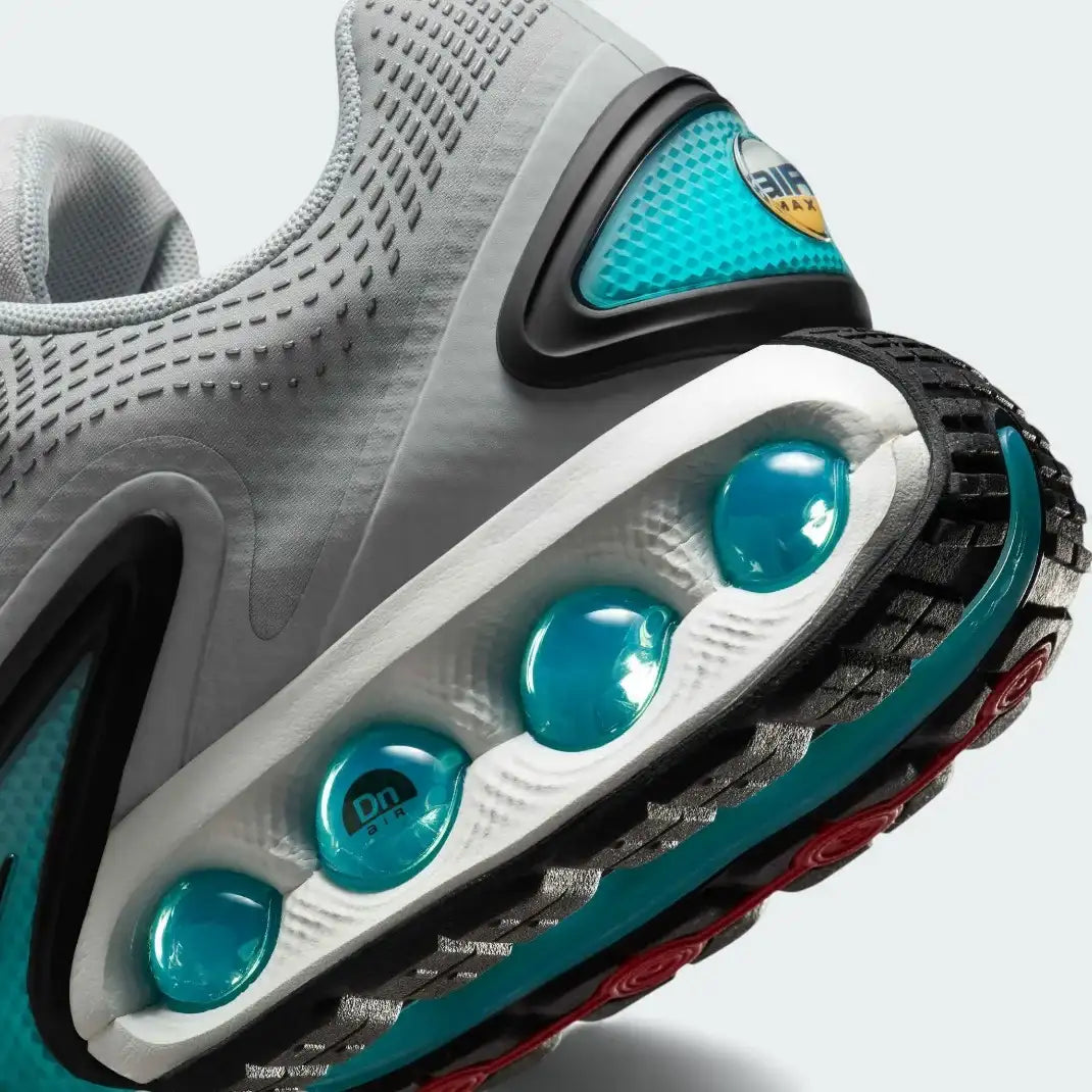 Detailed zoom on the outsole and midsole of the Nike Air Max DN Men's grey running shoes, highlighting the dual-pressure Dynamic Air cushioning system and robust rubber outsole.