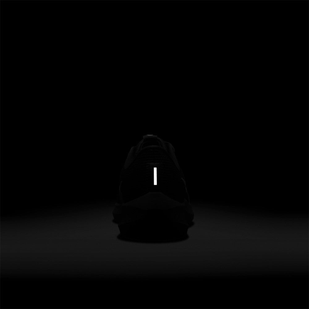 Demonstrates high-intensity night-time safety visibility, highlighting the bright vertical 3M reflective bar illuminated on the heel counter against a pitch-black background.