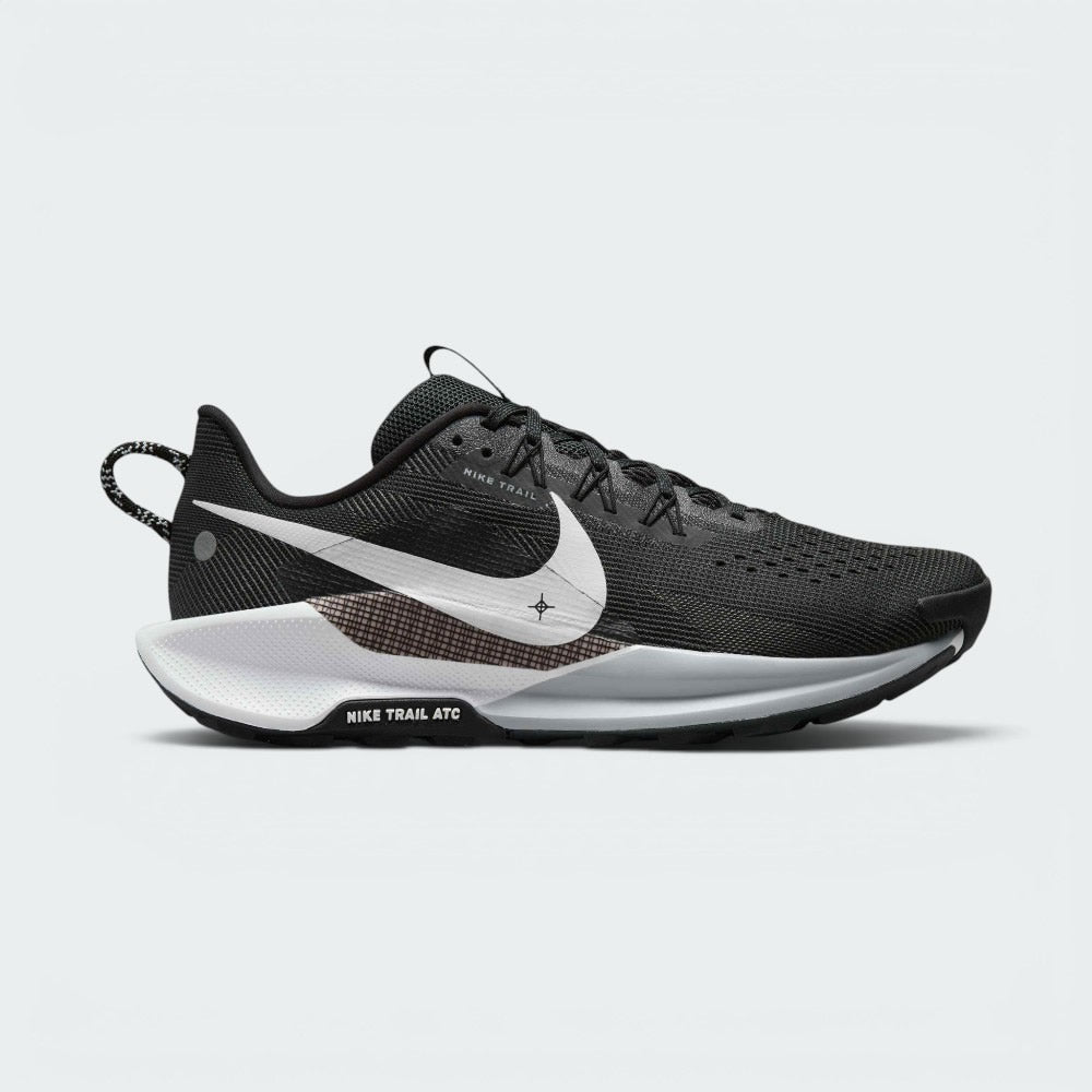 Highlights the outer profile of the shoe, featuring a crisp white Nike Swoosh sweeping across the black engineered mesh upper, an underlaid cross-hatch graphic panel, a grey and white ReactX foam midsole, and the debossed "NIKE TRAIL ATC" badge on the black outsole frame.