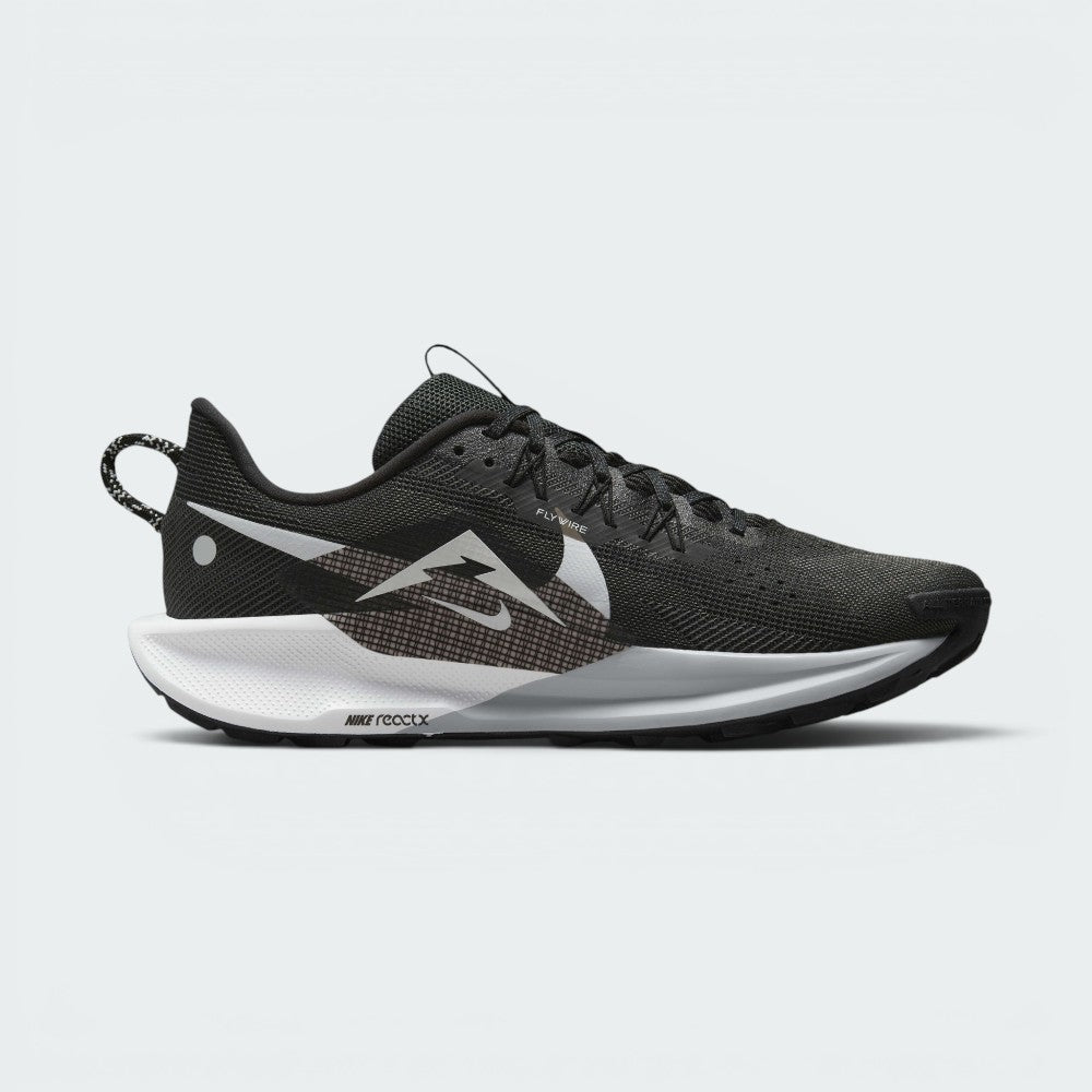 Shows the inner profile of the shoe, displaying a large stylized mountain peak graphic layered over the cross-hatch mesh pattern, Flywire eyelet cables, and the debossed "NIKE reactX" logo on the white heel midsole carrier.