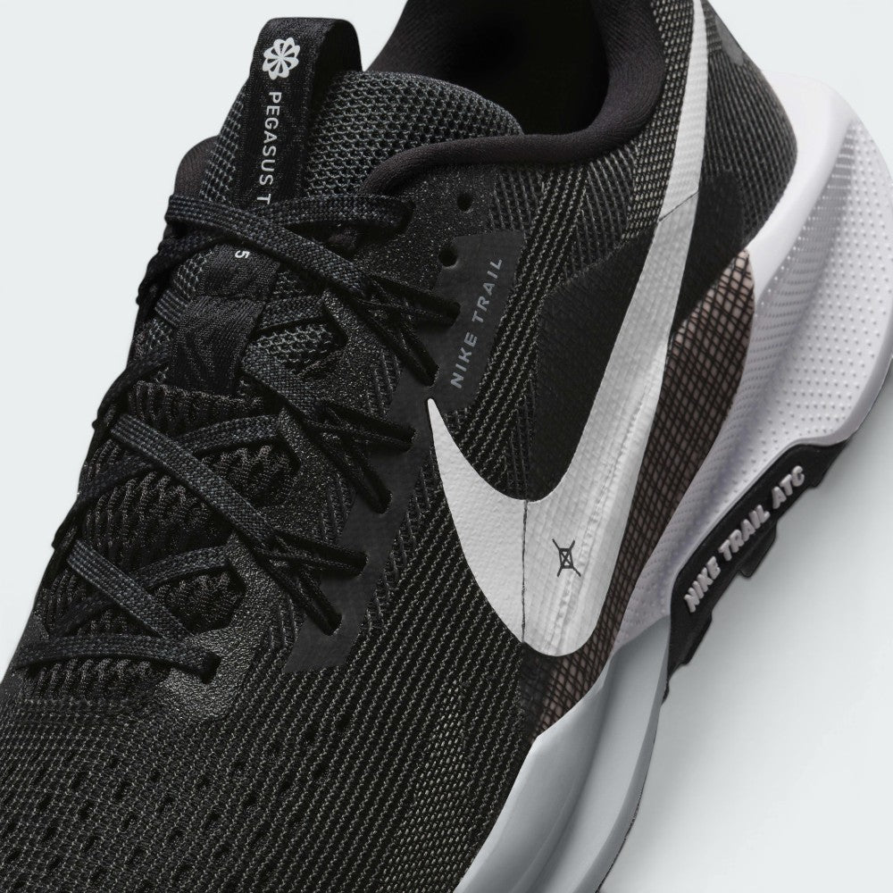 Close-up view of the lateral forefoot and lace tracking, detailing the open-hole mesh ventilation, Flywire lace loops, printed "NIKE TRAIL" eyelet tab, and the micro-textured white Swoosh over the grid-pattern midfoot overlay.