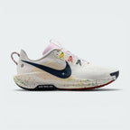 Highlights the lateral profile featuring an Armoury Navy Swoosh over a Summit White mesh upper, beige underlay grid panel, yellow and coral Flywire lace loops, paint-splattered ReactX foam midsole, and the "NIKE TRAIL ATC" outsole badge.