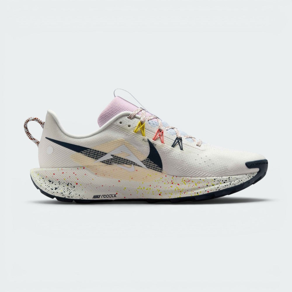 A Nike running shoe in a side profile view, featuring a white and light beige Flyknit upper with colorful speckles on the midsole, a black Swoosh, and multicolor laces.