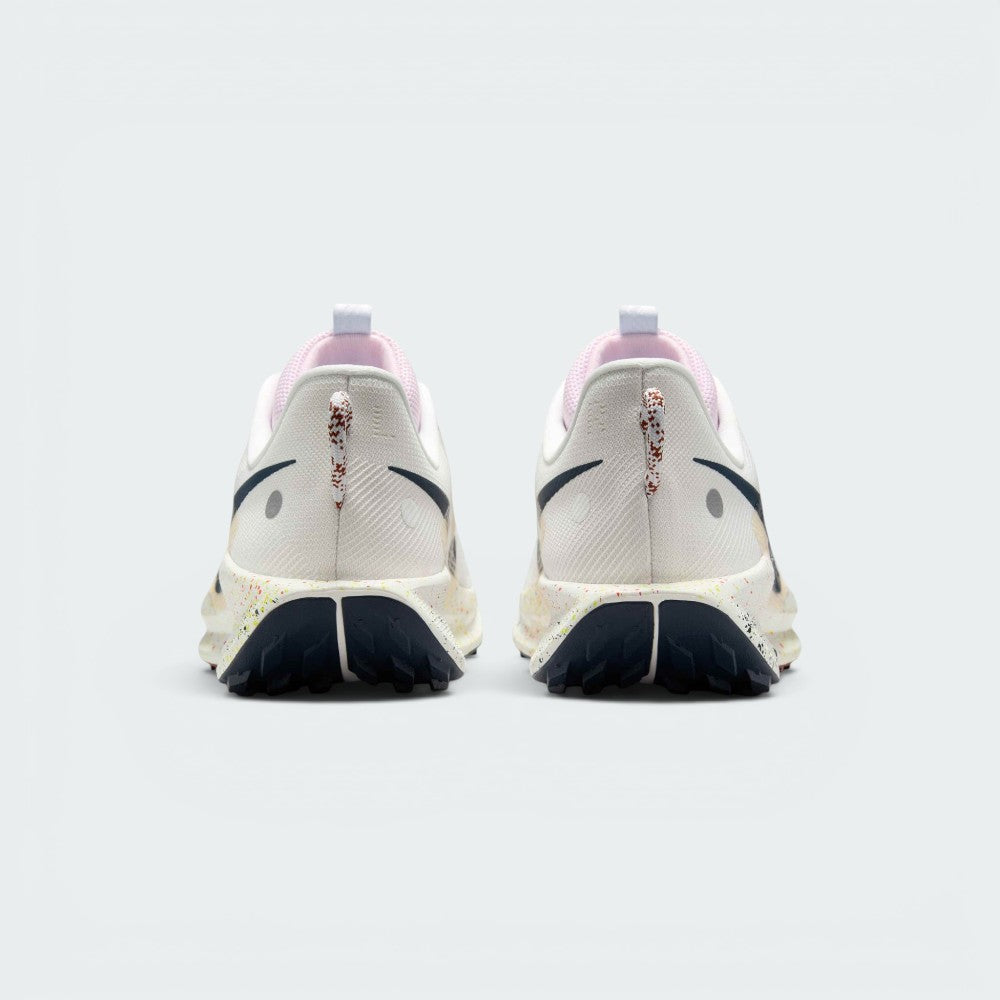 Focuses on the rear profile, highlighting the flecked pull loops, circular reflective dots on the heel counters, pink tongue collars, and the wide footprint of the splattered ReactX midsole base.