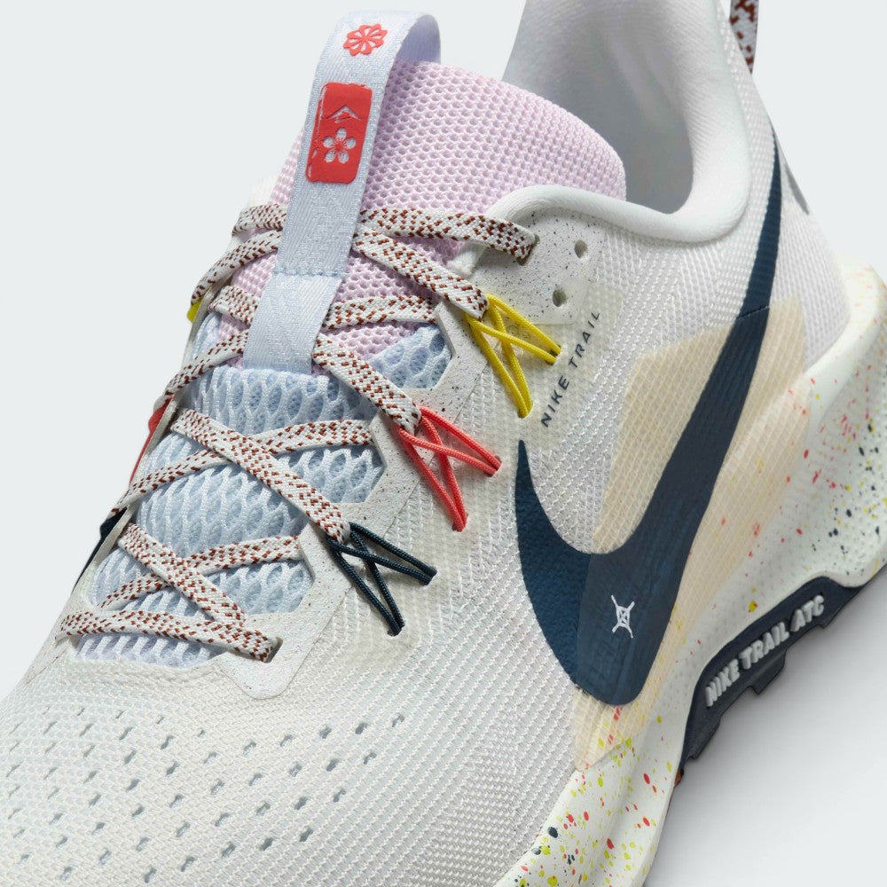 Details the micro-precision of the open-cell forefoot mesh upper, showing the flecked laces, floral tongue badge, and vibrant yellow and coral Flywire cables.