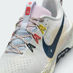 Details the micro-precision of the open-cell forefoot mesh upper, showing the flecked laces, floral tongue badge, and vibrant yellow and coral Flywire cables.