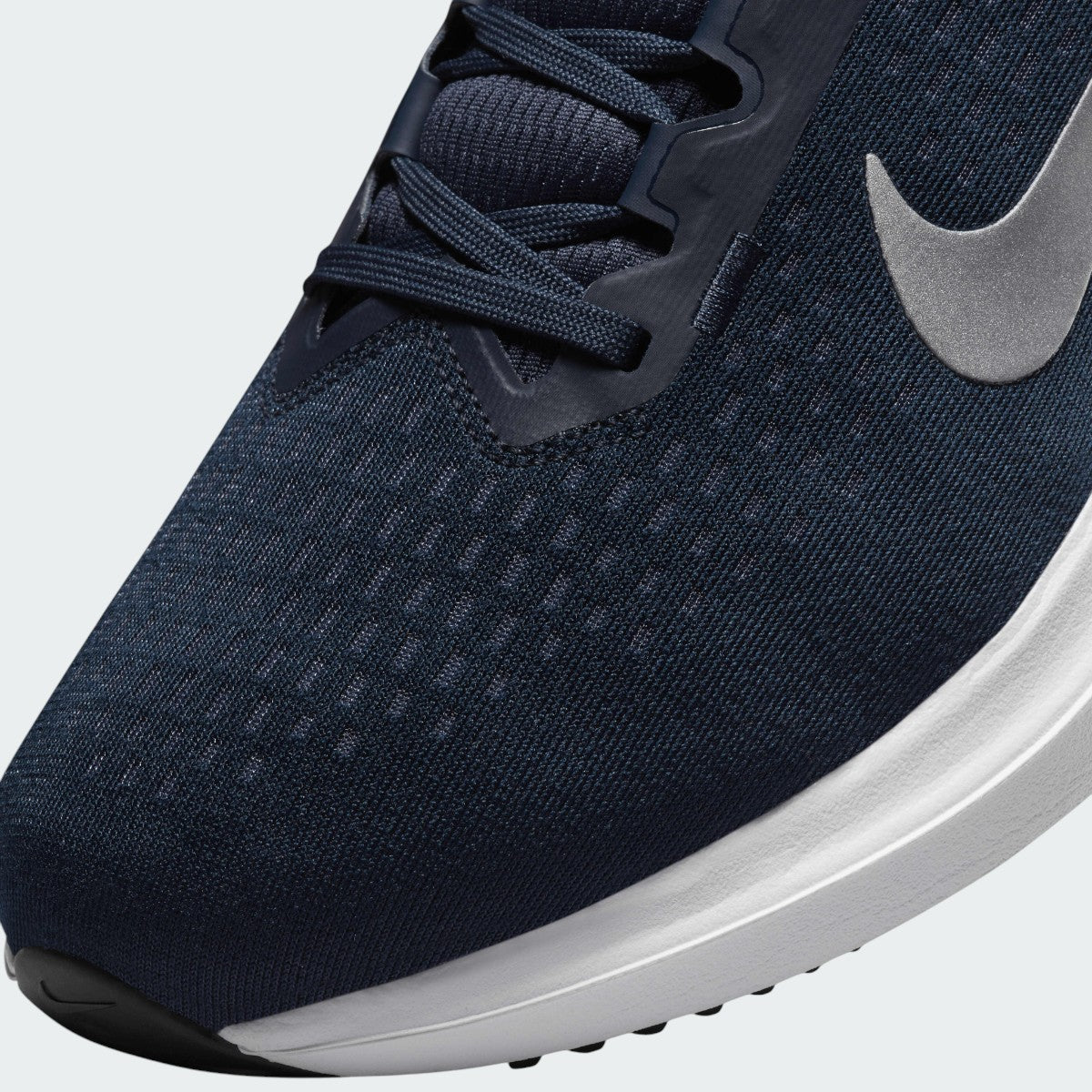 Close-up zoom on the front of the Nike Air Winflo 10 Men's navy running shoes, showing the mesh upper texture, lacing system, and synthetic overlays.