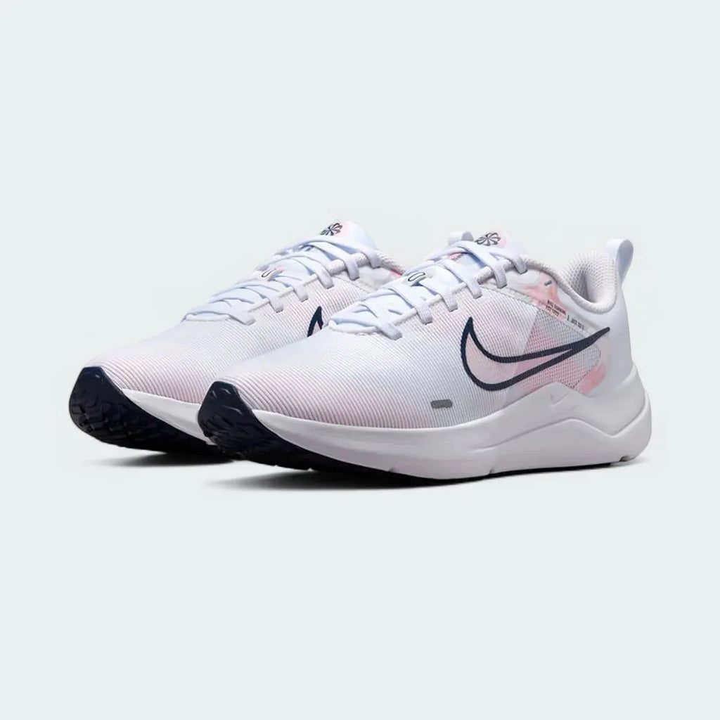 Angled view of two Nike Downshifter 12 Premium Women's white training shoes, side by side, showcasing their versatile design and cushioned profile.