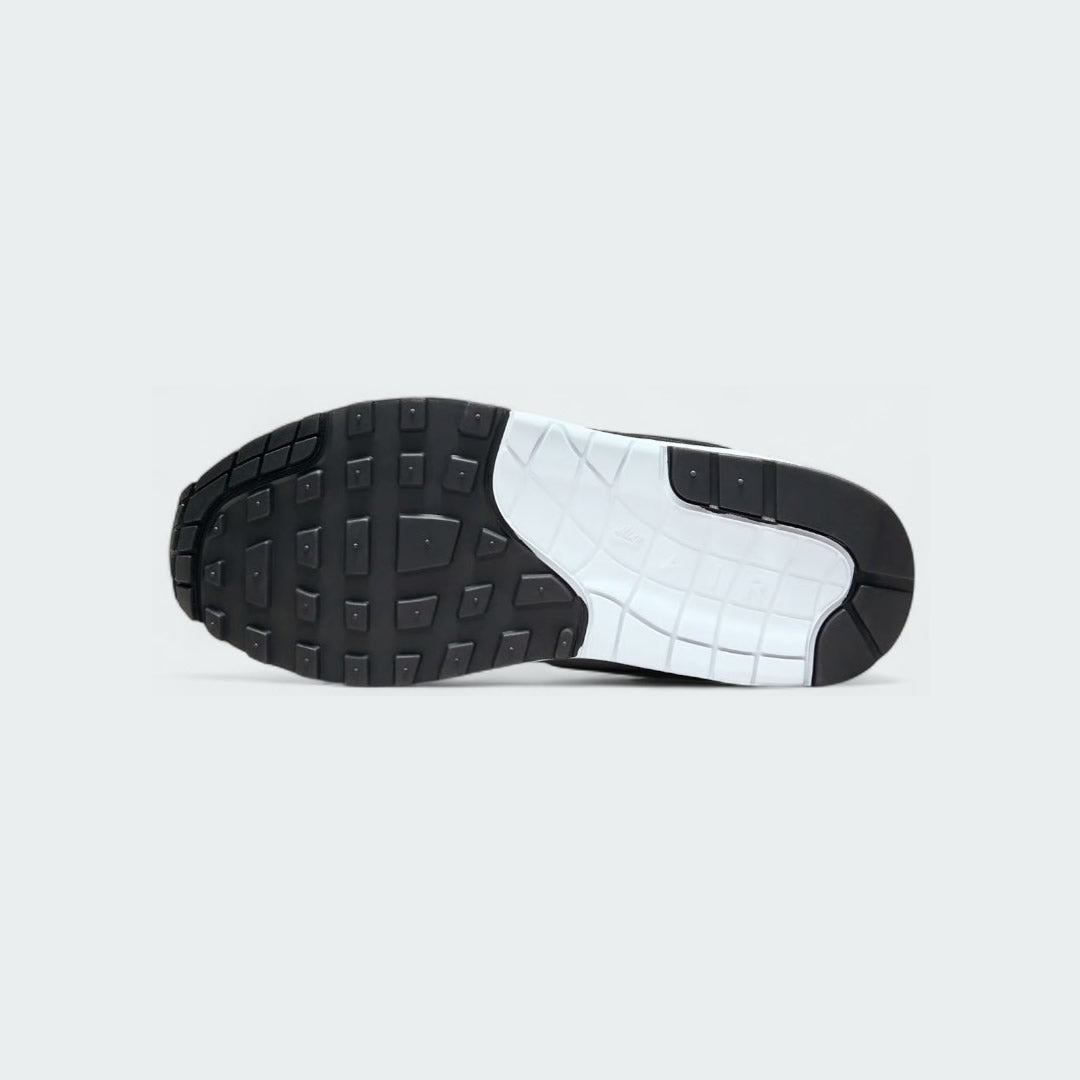 View of the outsole of the Nike Air Max 1 Women's white trainers, showing the durable rubber waffle tread pattern for traction.