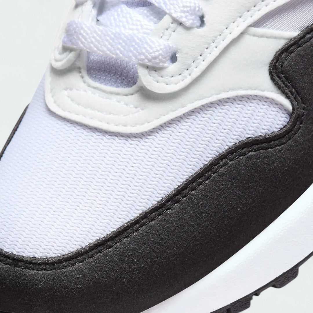 Close-up zoom on the front of the Nike Air Max 1 Women's white trainers, showing the mesh toe box, lacing system, and layered synthetic overlays.