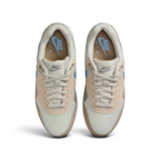 Top-down view of a pair of Nike Air Max 1 Juniors' trainers in light brown and blue, highlighting their classic silhouette and lace-up closure.