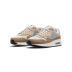 Angled view of two Nike Air Max 1 Juniors' trainers in light bone, psychic blue, and black, side by side, showcasing their timeless design and layered upper.