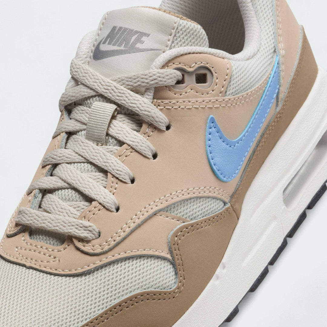 Close-up zoom on the front of the Nike Air Max 1 Juniors' trainers, showing the mesh toe box, lacing system, and textured leather overlays.