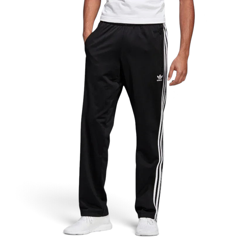 Adidas Firebird Track Pants Men's in black, model worn front view showing white 3-Stripes down the legs, Trefoil logo on the hip, and zipped pockets. Main image