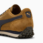 Close-up rear angle focusing on the suede heel counter, New Navy leather moustache tab stamped with a gilded metallic PUMA Cat logo, and the studded rubber outsole extending upwards to protect the Achilles.