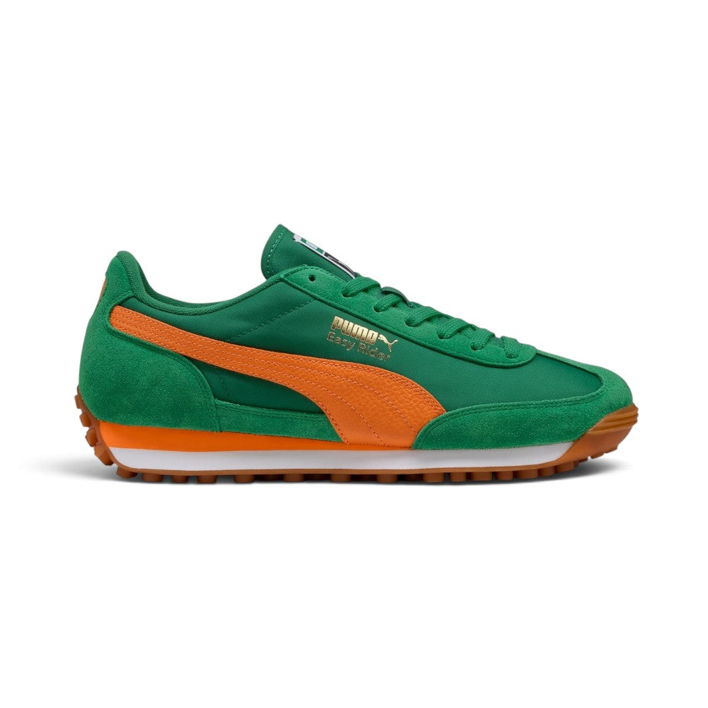 Lateral view showing the vibrant Archive Green textile upper, rich green suede toe and heel overlays, bright Rickie Orange leather Formstrip, metallic gold foil "PUMA Easy Rider" script, dual-layer orange and white EVA wedge midsole, and gum rubber studded outsole wrapping at the toe and heel. Main image