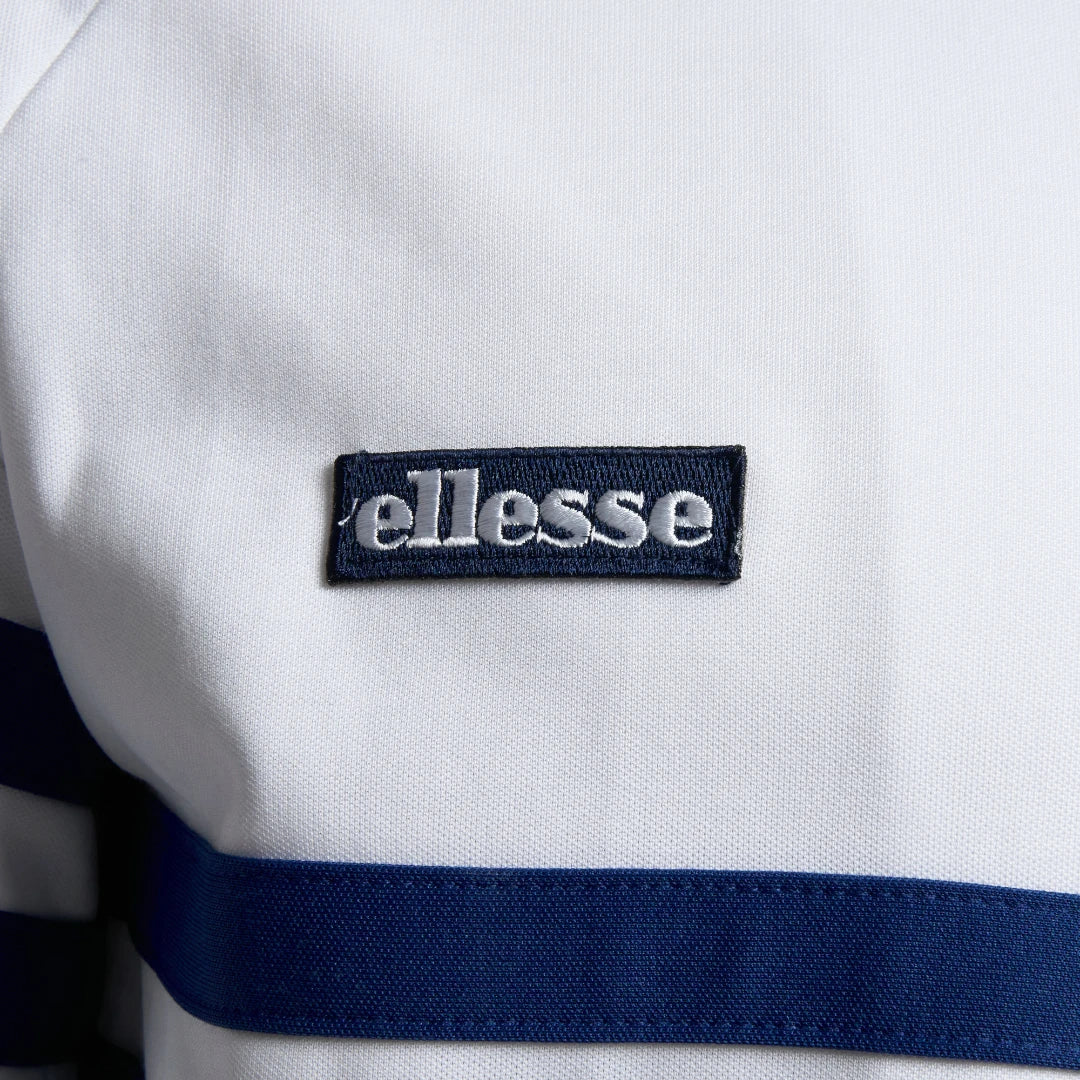 Close-up zoom on the fabric of the Ellesse Rimini Track Jacket in white, showing the smooth tricot texture and the embroidered Ellesse logo on the chest.