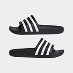 Black Adidas slides with white stripes on a light gray background