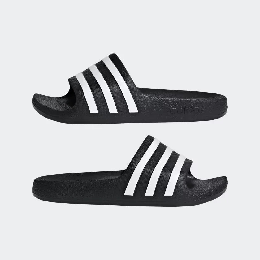 Black Adidas slides with white stripes on a light gray background