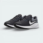 Angled shot of both Nike Revolution trainers side by side, showcasing the sleek aerodynamic silhouette and the tonal grey color layers.