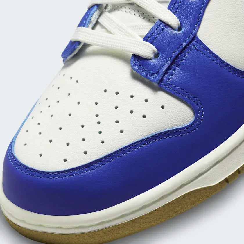 Close-up of Nike Dunk Low Women's White Leather Trainers FB7173-141 showing smooth leather texture, stitching, and tongue branding