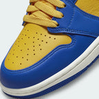 Close-up zoom on the front of the Air Jordan 1 Hi Retro OG Women's yellow and blue trainers, showing the perforated toe box, lacing system, and textured leather upper.