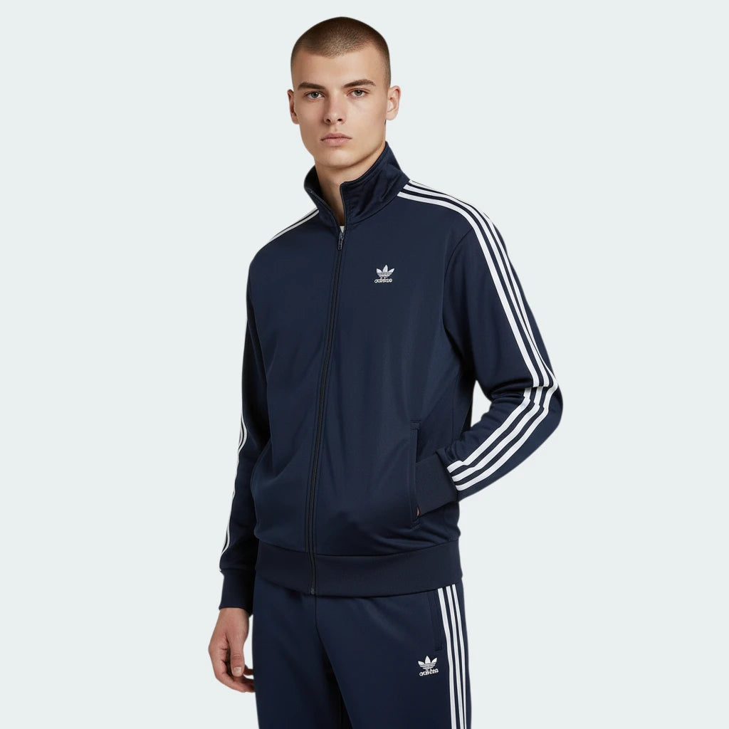 Adidas Firebird Track Jacket Men's in collegiate navy, front view showing full zip, stand-up collar, white 3-Stripes on sleeves, and Trefoil logo worn my model