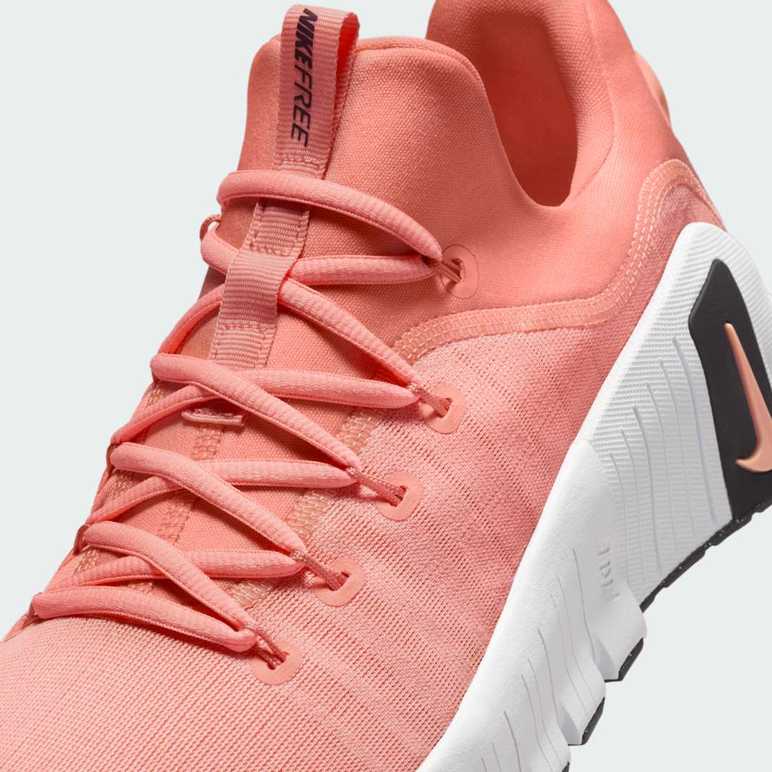 Close-up zoom on the front of the Nike Free Metcon 5 Men's orange training shoes, showing the breathable mesh upper texture, lacing system, and flexible toe area.