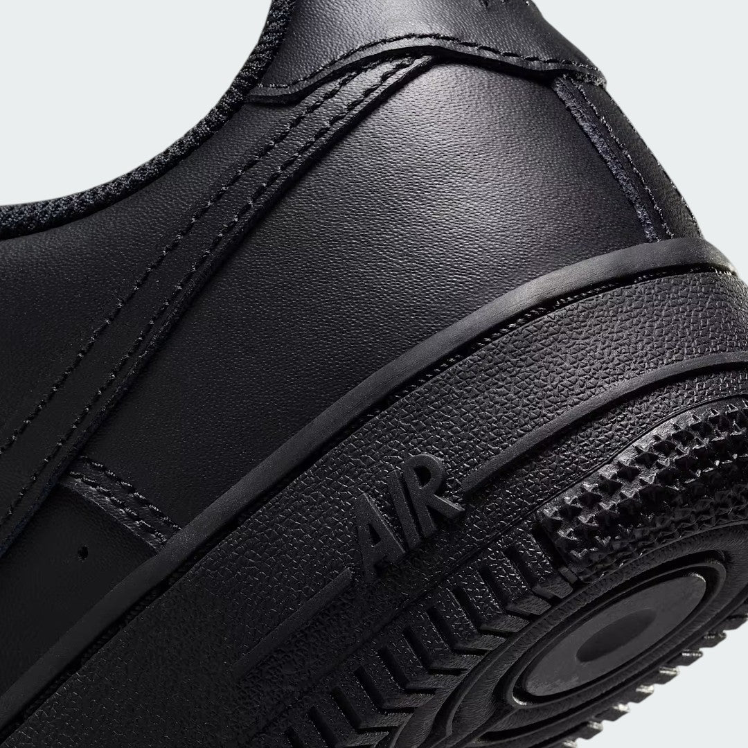 Detailed zoom on the outsole and midsole of the Nike Air Force 1 Juniors' black trainers, highlighting the cushioned midsole and durable rubber outsole.