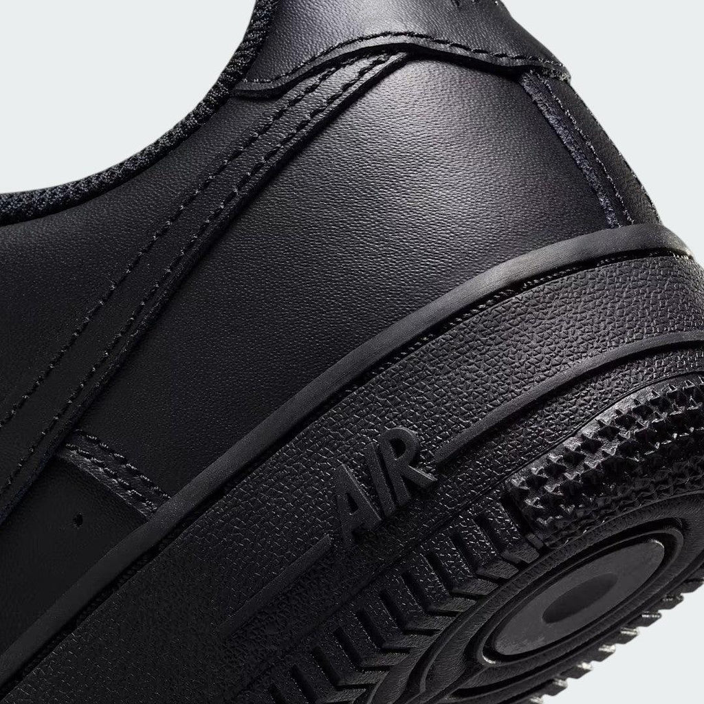 Detailed zoom on the outsole and midsole of the Nike Air Force 1 Juniors' black trainers, highlighting the cushioned midsole and durable rubber outsole.
