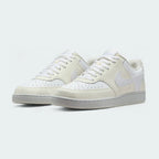 Angled view of two Nike Court Vision Lo Next Nature Women's trainers in white and white, side by side, showcasing their clean aesthetic and retro style.