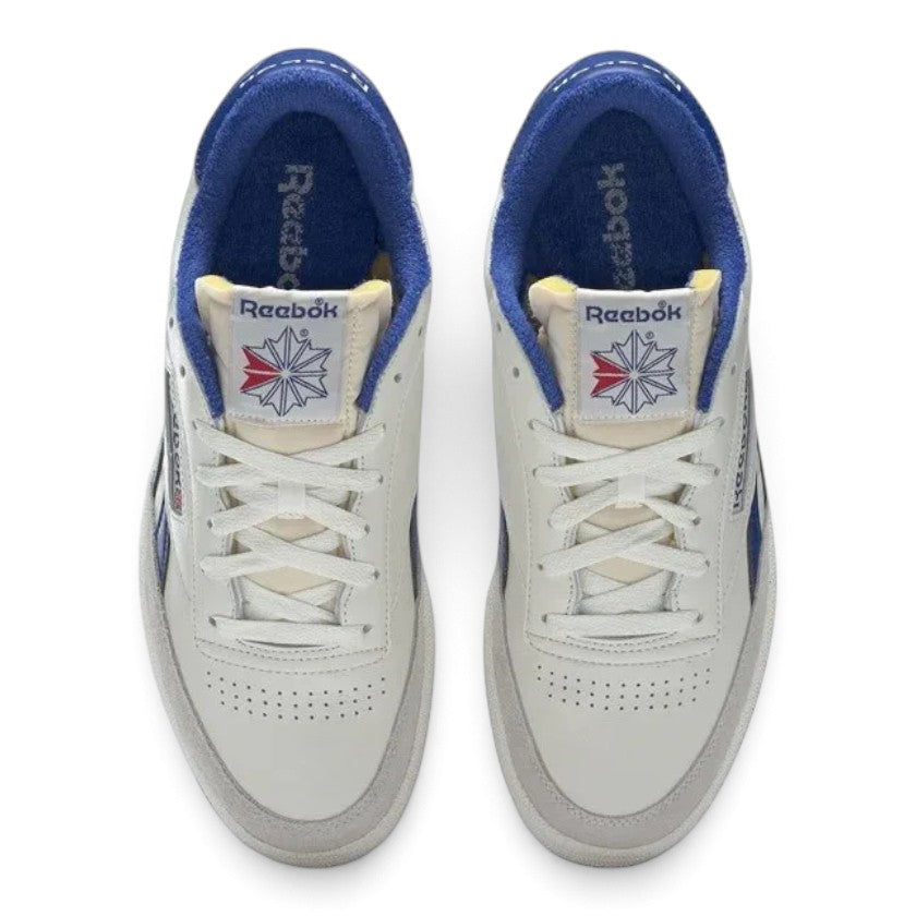 Overhead top-down view of both sneakers side by side, featuring the white lace-up closure, perforated toe vamps, exposed foam tongue construction with vintage woven labels, and plush royal blue terry cloth linings.