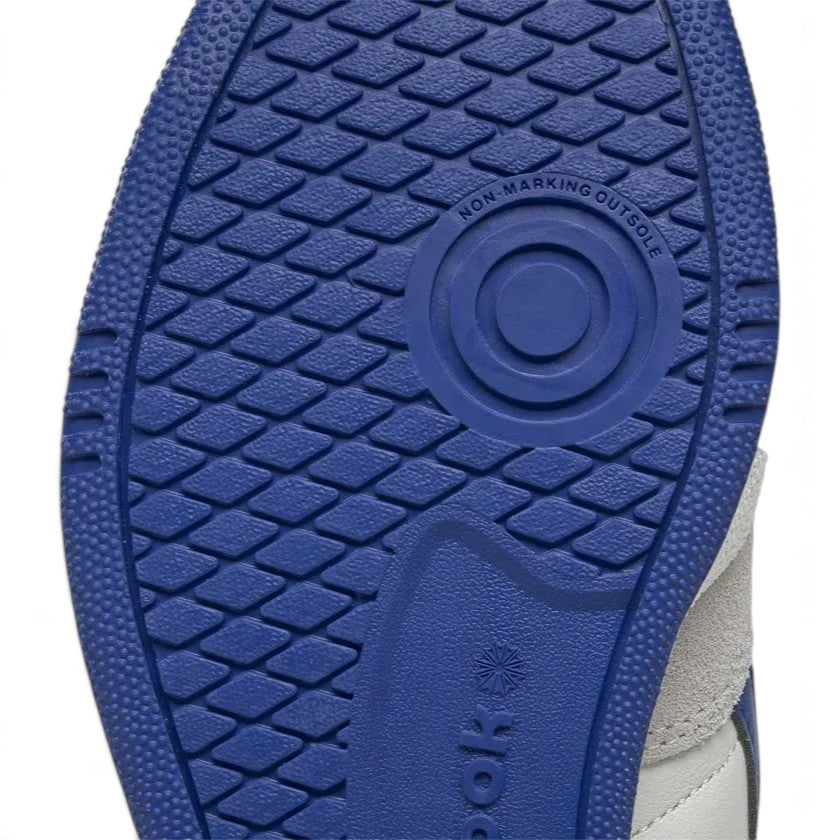 Close-up detailed shot of the royal blue rubber outsole tread pattern, highlighting the textured grip, non-marking outsole stamp, pivot point, and embossed Reebok branding.