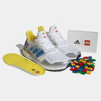 Angled view of two Adidas Ultraboost DNA x Lego Men's trainers in white and blue, side by side, showcasing their bold design and Lego-inspired details.