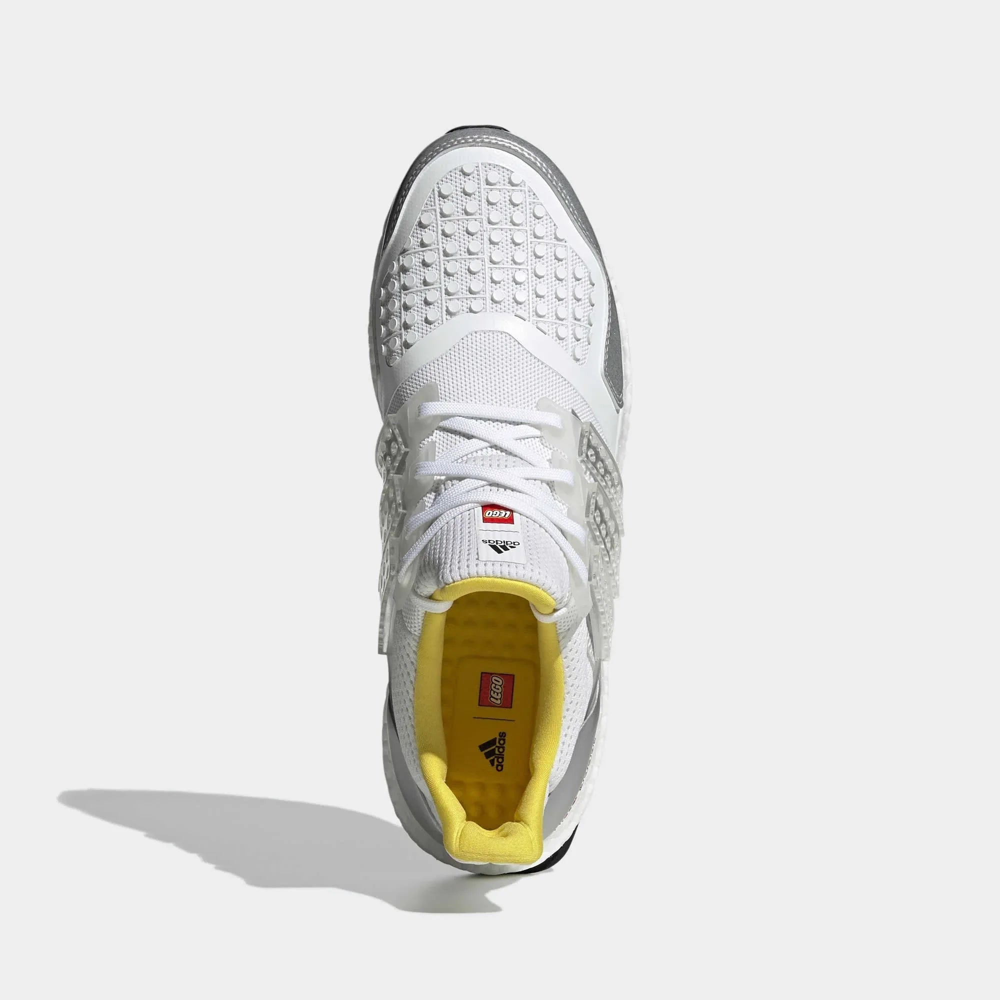 Top-down view of a pair of Adidas Ultraboost DNA x Lego Men's trainers in white, highlighting their seamless Primeknit construction and unique lacing.